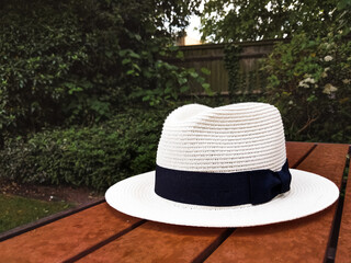White hat with black detail on a wooden table in the garden