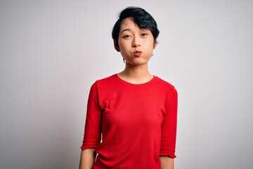 Young beautiful asian girl wearing casual red t-shirt standing over isolated white background...