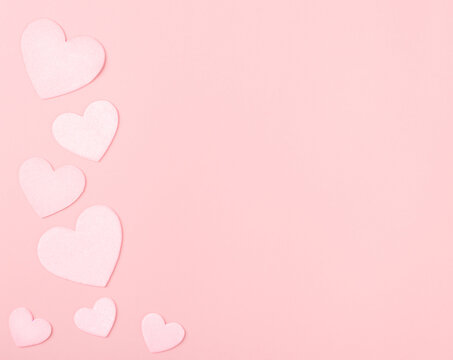 Pastel Pink Valentine Hearts on Pink Paper with space for copy, text or your words.  It's a horizontal photo with an above view and room for cropping.