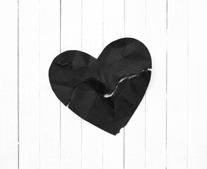 Black Heart representing Evil or Disease on White Wood Board Background with copy space.