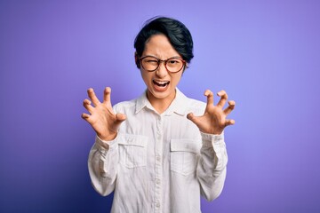 Young beautiful asian girl wearing casual shirt and glasses standing over purple background smiling...