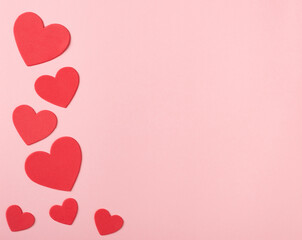 Bright Red Valentine Hearts on Pink Paper with space for copy, text or your words.  It's a horizontal photo with an above view and room for cropping.