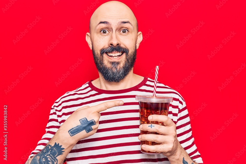 Poster Young handsome man drinking glass of cola beverage smiling happy pointing with hand and finger