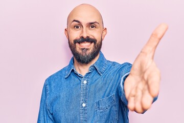 Fototapeta premium Young handsome man wearing casual clothes smiling friendly offering handshake as greeting and welcoming. successful business.