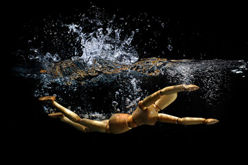 Wooden stick figure jumping in water splashing