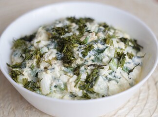 salad of cucumbers, eggs, green onions, seasoned with sour cream, decorated with dill