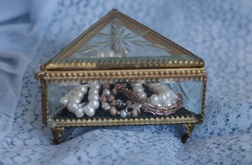 Pearl beads and gold bracelets in a beautiful glass box