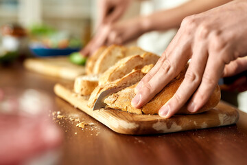 Close up of male hands cutting tasty homemade bread on the wooden board. Vegetarianism, healthy food concept.