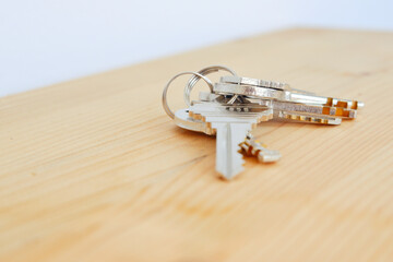 Bunch of keys on a shaped keychain at wooden table background. Concept for real estate or renting home with copy space,Close up.
