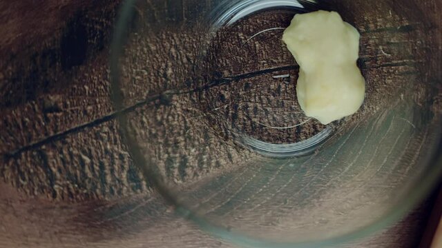 A measure of 1 TBSP of Garlic paste in a transparent glass bowl on a brown wooden table. Rotating camera capturing a food ingredient.