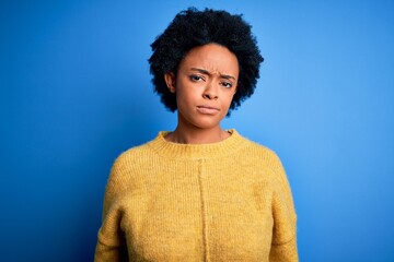 Fototapeta na wymiar Young beautiful African American afro woman with curly hair wearing yellow casual sweater looking sleepy and tired, exhausted for fatigue and hangover, lazy eyes in the morning.