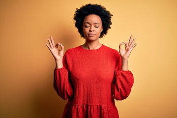 Young beautiful African American afro woman with curly hair wearing casual sweater relax and smiling with eyes closed doing meditation gesture with fingers. Yoga concept.
