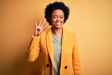 Obraz na płótnie Canvas Young beautiful African American afro businesswoman with curly hair wearing yellow jacket showing and pointing up with fingers number four while smiling confident and happy.