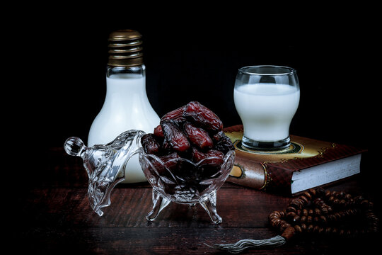 Malay translation book of Al-Quran, dried dates, glass of milk isolated on black background. Terjemahan means translation in English. Low key photography.