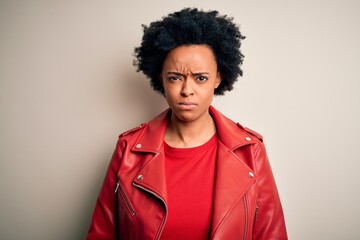 Young beautiful African American afro woman with curly hair wearing casual red jacket skeptic and...
