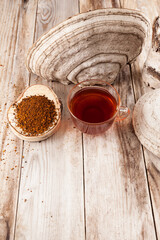 Cup of tea chaga and a large birch chaga mushroom on a wooden table in a rustic style