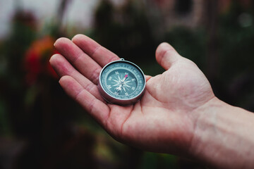 a guy holding a gray compass in a garden