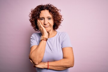 Fototapeta na wymiar Middle age beautiful curly hair woman wearing casual t-shirt over isolated pink background thinking looking tired and bored with depression problems with crossed arms.