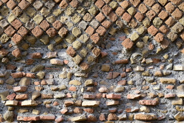 Closeup historical ancient Roman masonry building technique, called Opus Reticulatum, with partly damaged stone wall detail texture.