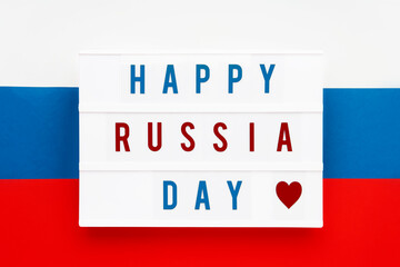 HAPPY RUSSIA DAY written in lightbox on russian flag background. Independence day date. Top view