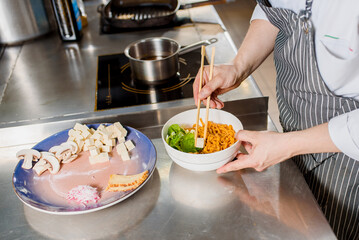 White soft cheese is put on plate. Chef cooks spaghetti noodles for ramen soup. Cooking ramen soup with meat, mushrooms, radish, eggs.