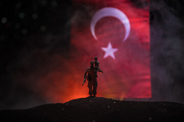 Silhouette of soldier with rifle against a turkish flag. Selective focus