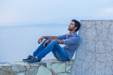 Man thinking sitting on a concrete bridge above the sea