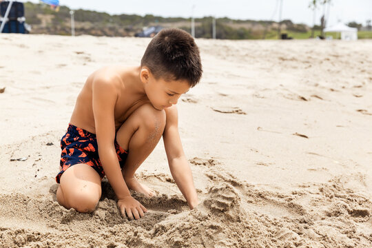 Kid playing with sand on a tropical beach at summer vacation, travel and holiday concept