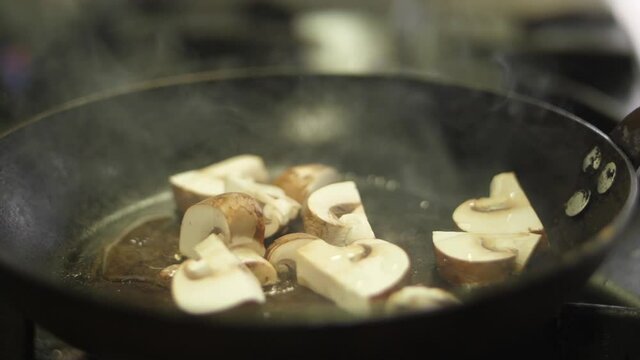chef cooking sauteed mushrooms in pan slow motion