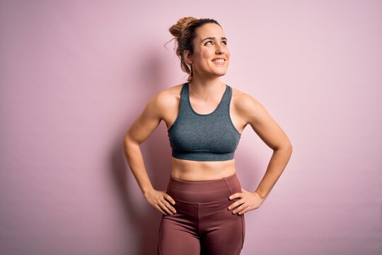 Young beautiful blonde sportswoman doing sport wearing sportswear over pink background smiling looking to the side and staring away thinking.