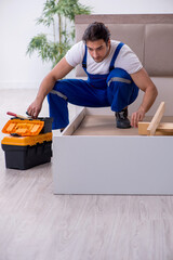 Young male contractor installing furniture at home