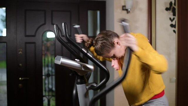 girl loses strength during training and slides down the sport training machine, side view