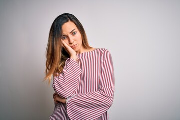 Young beautiful blonde woman with blue eyes wearing stiped t-shirt over white background thinking looking tired and bored with depression problems with crossed arms.