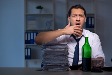 Alcohol addicted businessman working late in the office