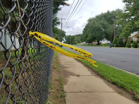 yellow caution tape on chain link fence and sidewalk and road
