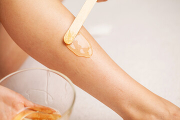 Skin care, a woman applies wax to her leg to remove hair