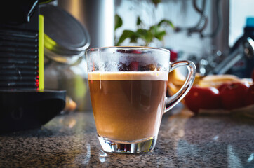 A cup of coffee with milk over a kitchen table. Afternoon coffee time mood.