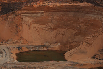 Red clay quarry. Clay quarry. Top view of a sand excavation site. Earth rocks are digging for building materials. Beautiful natural landscape to the land. Quarry with sand, sand loading, ground water,