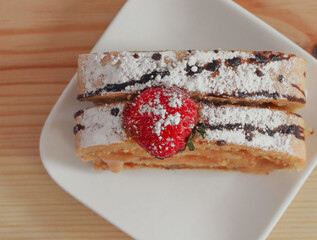 Sponge cake with tea.....One slice of biscuit roll and a mug of black tea on a wooden table, closeup