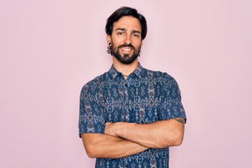 Young handsome hispanic bohemian man wearing hippie style over pink background happy face smiling with crossed arms looking at the camera. Positive person.