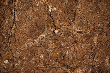 Texture of land dried up by drought, the ground cracks background with grunge. Black Soil Texture Background. Top View of a Dark Ground Surface. Close Up Macro View of Dirt and Stones. Text Space.