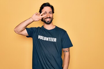 Young handsome hispanic volunteer man wearing volunteering t-shirt as social care Doing peace...