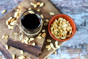 Selective focus. A glass of coca cola and peanuts. Salted peanuts in a glass with cola. American food. Traditional American snack. High-calorie drinks.