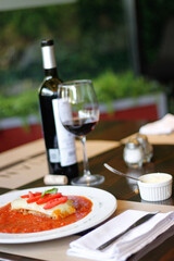 Lasagna acompañada de copa y botella de vino tinto 