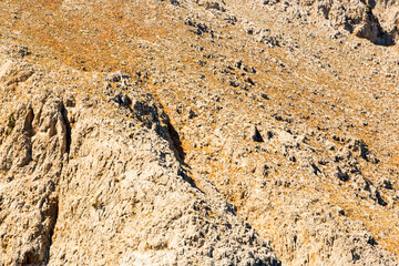 Fototapeta na wymiar texture of a mountain with crevices bright daylight, grass on rocks