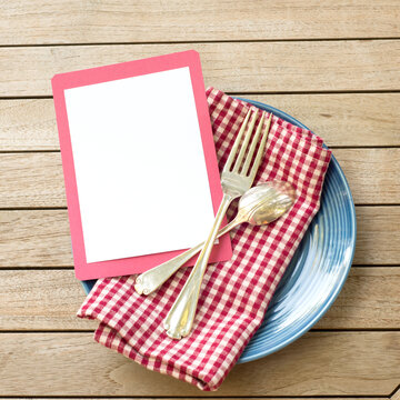 Summer Picnic Outdoor Table Placesetting With Red White And Blue Colors With Fork And Spoon With A Blank Card For Your Words, Text, Copy Or Design.  A Flat Lay And Square Crop From Top Down View