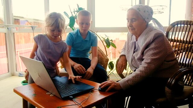 grandchildren teach 80 year old grandmother to work on a smartphone. playing with a smartphone. Make purchases online. are photographed. on the veranda of the house. Communicate on the Internet