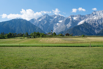Green meadows along the rocky mountain range with typical small Austrian church, Mieming, Austria