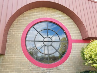 large circular glass window with wasp nest on brick building