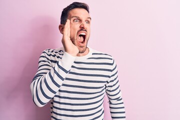 Fototapeta premium Young handsome man wearing casual striped sweater standing over isolated pink background shouting and screaming loud to side with hand on mouth. Communication concept.